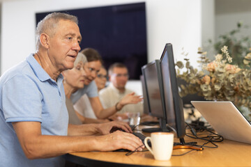 Obraz premium Curious mature man engaged in IT training during computer courses for adults