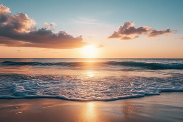 Fototapeta premium The image captures the tranquil beauty of ocean waves gently approaching a sandy shoreline during a serene sunset, with clouds alight in the sky above.