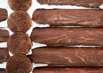  A close-up of a wooden log cabin wall covered with a light dusting of snow,