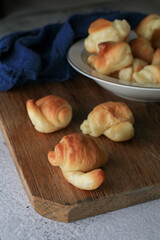 Mini croissant eat with coffee or tea in white pate on wooden board. French bakery, sweet dough dessert. Breakfast baked.