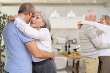 Obraz premium Couple dance at a house party in an apartment for elderly friends