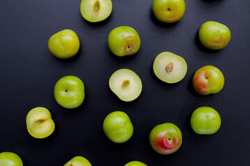 Fresh green plum fruit on dark background.