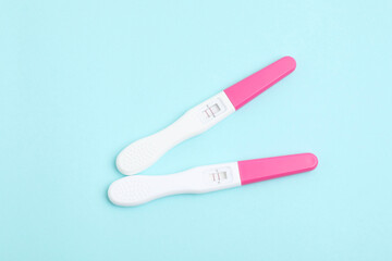 Pregnancy tests on light blue background, top view