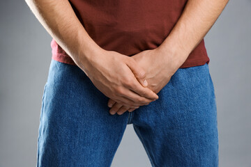 STD (sexually transmitted diseases). Man suffering from symptoms on grey background, closeup