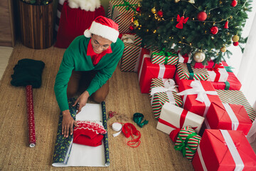 Naklejka premium Photo of handsome good mood guy wear green sweater packing noel xmas gifts indoors room home house