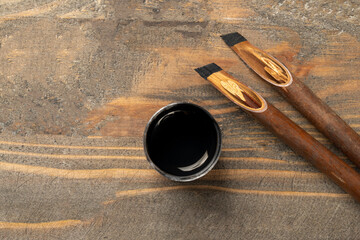 Calligraphy reeds covered ink with inkwell on wooden background