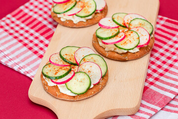 Light Breakfast or Diet Eating - Crispy Cracker Sandwich with Cream Cheese, Fresh Cucumber and Radish on Wooden Cooking Board on Magenta Background