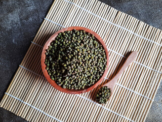 Flat lay photo style of mung beans in a bowl above the sushi roller. 