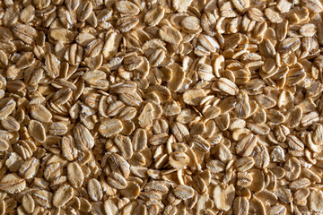 Uncooked Oat Flakes background - Top View, Flat Lay. Scattered Dry and Raw Oat Flakes. Healthy Breakfast and Diet Eating Ingredients