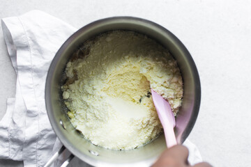 Overhead view of tuwon madara dough in a silver saucepan, nigerian alawar madara milk candy, process of making tuwon madara or milk fudge