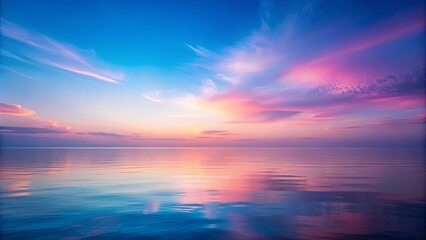 Obraz premium The tranquil expanse of the sea reflects the vibrant hues of a fading sunset, painting the water with a delicate tapestry of pink and blue.