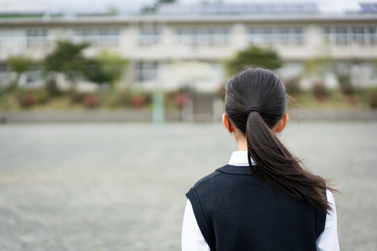 校舎を眺める女子生徒の後ろ姿
