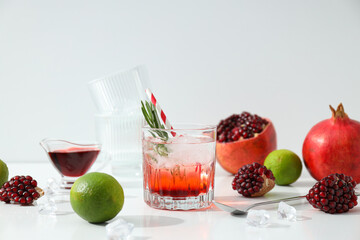 Red cocktail with fresh pomegranate and lime on a white background