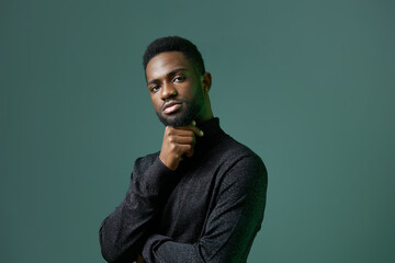 Thoughtful african american man contemplating with hand on chin in studio setting