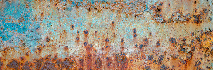 Close-up of a rusty metal surface featuring blue peeling paint, corrosion patterns, and textured decay.