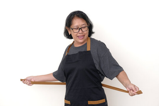 Asian woman fixing her black apron, getting ready to cook in the kitchen