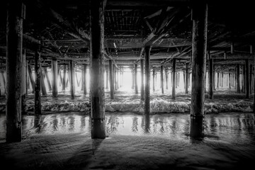 A captivating view under the Santa Monica Pier, showcasing the intricate interplay of light and shadow on the ocean water.