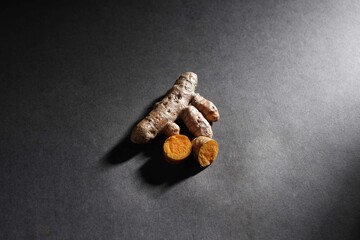 fresh turmeric root and slices isolated on dark background, turmeric (Curcuma longa Linn), spice concept