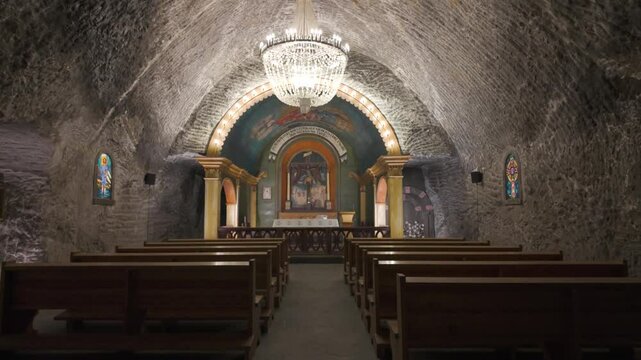 Underground chapel inside Wieliczka Salt Mines in Poland, with ornate salt carvings and dim lighting across stone walls and wooden pews with altar
