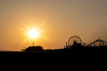 Stunning sunset at Santa Monica Pier, highlighting the iconic Ferris wheel silhouetted against the vibrant sky.