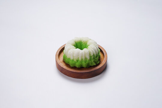 Putu Ayu is served on a wooden plate with white background. It is a traditional dessert made from steamed rice flour and topped with grated coconut, a classic Indonesian cake