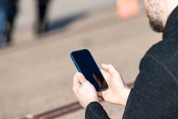 A man holding his phone, showcasing the use of mobile technology for work and connectivity. 