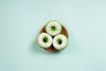 Putu Ayu is served on a wooden plate with green background. It is a traditional dessert made from steamed rice flour and topped with grated coconut, a classic Indonesian cake