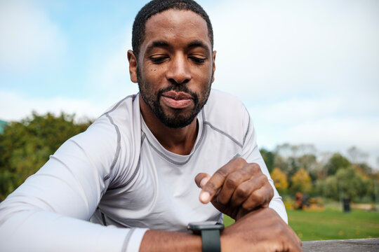 Focused black athlete checking smartwatch after training outdoors