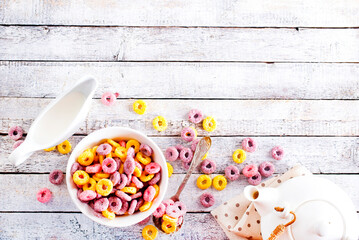 Falling colorful corn rings into bowl on white table