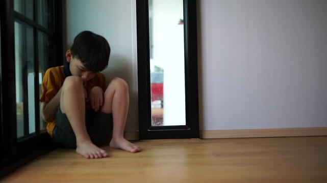 A sad young boy sat in the corner crying and covering her face with her hands. The concept of child abuse in the family Parents punish their children into a corner, the child is depressed, crying, lif
