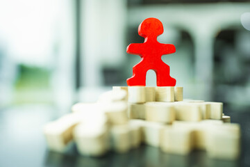 A red wooden figure standing with other person figure lie on floor, Concept of leadership, successful competition winner and Leader with influence and winner among the losers.