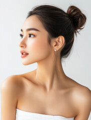 Fototapeta premium profile portrait of Asian woman with bun hairstyle, showcasing natural beauty and elegance. Her skin is flawless, and she has serene expression