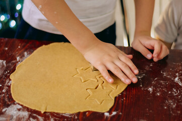 a child cuts out holiday cookies from gingerbread dough using cookie cutters