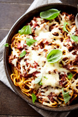 Baked spaghetti pasta with mozzarella cheese. Wooden background. Top view.