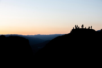 Silhouette of group of people watching the sunset in the mountains