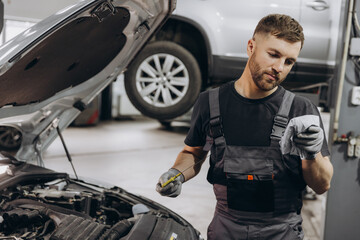 Car mechanic checking the engine oil level in the service center