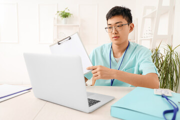 Male Asian doctor with laptop video chatting in clinic