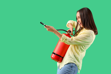 Young woman with fire extinguisher on green background