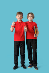 Cute boys in school uniform showing thumbs-up on blue background