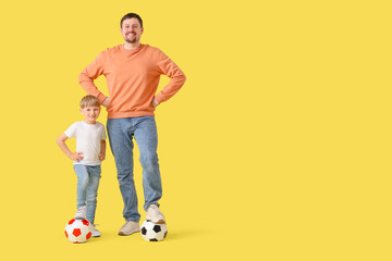 Fototapeta premium Young father and little son with soccer balls on yellow background