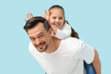 Daughter sitting at father's back on blue background. Father's Day celebration