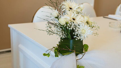 A small, stylish bouquet of fresh white flowers adorns a festive table in the restaurant.