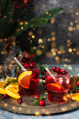 Cranberry boozy Christmas cocktail with ice and rosemary on dark background. Festive spiced drink...