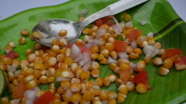 Boiled corn Chaat. Indian style corn salad that's sweet, spicy and tangy. It is mixed with chaat masala, roasted cumin powder, red chili powder, coriander leaves, onion and tomatoes. Indian snacks.