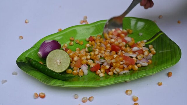 Boiled corn Chaat. Indian style corn salad that's sweet, spicy and tangy. It is mixed with chaat masala, roasted cumin powder, red chili powder, coriander leaves, onion and tomatoes. Indian snacks.