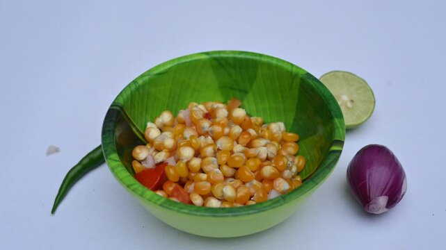 Boiled corn Chaat. Indian style corn salad that's sweet, spicy and tangy. It is mixed with chaat masala, roasted cumin powder, red chili powder, coriander leaves, onion and tomatoes. Indian snacks.