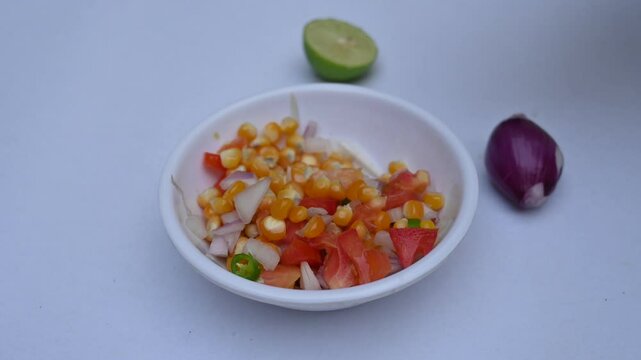 Boiled corn Chaat. Indian style corn salad that's sweet, spicy and tangy. It is mixed with chaat masala, roasted cumin powder, red chili powder, coriander leaves, onion and tomatoes. Indian snacks.