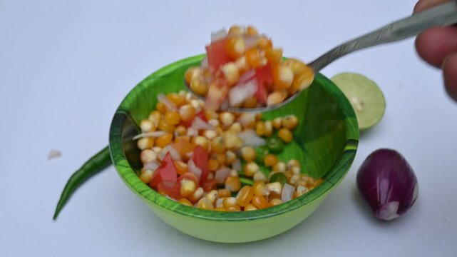 Boiled corn Chaat. Indian style corn salad that's sweet, spicy and tangy. It is mixed with chaat masala, roasted cumin powder, red chili powder, coriander leaves, onion and tomatoes. Indian snacks.