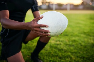 Rugby, hands and man with ball for sports, game or competition at pitch. Player, oval and closeup of equipment at field for training match, exercise and athlete kneeling for fitness workout outdoor