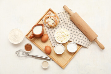 Wooden board with different ingredients for preparing sweet cinnamon roll on white background